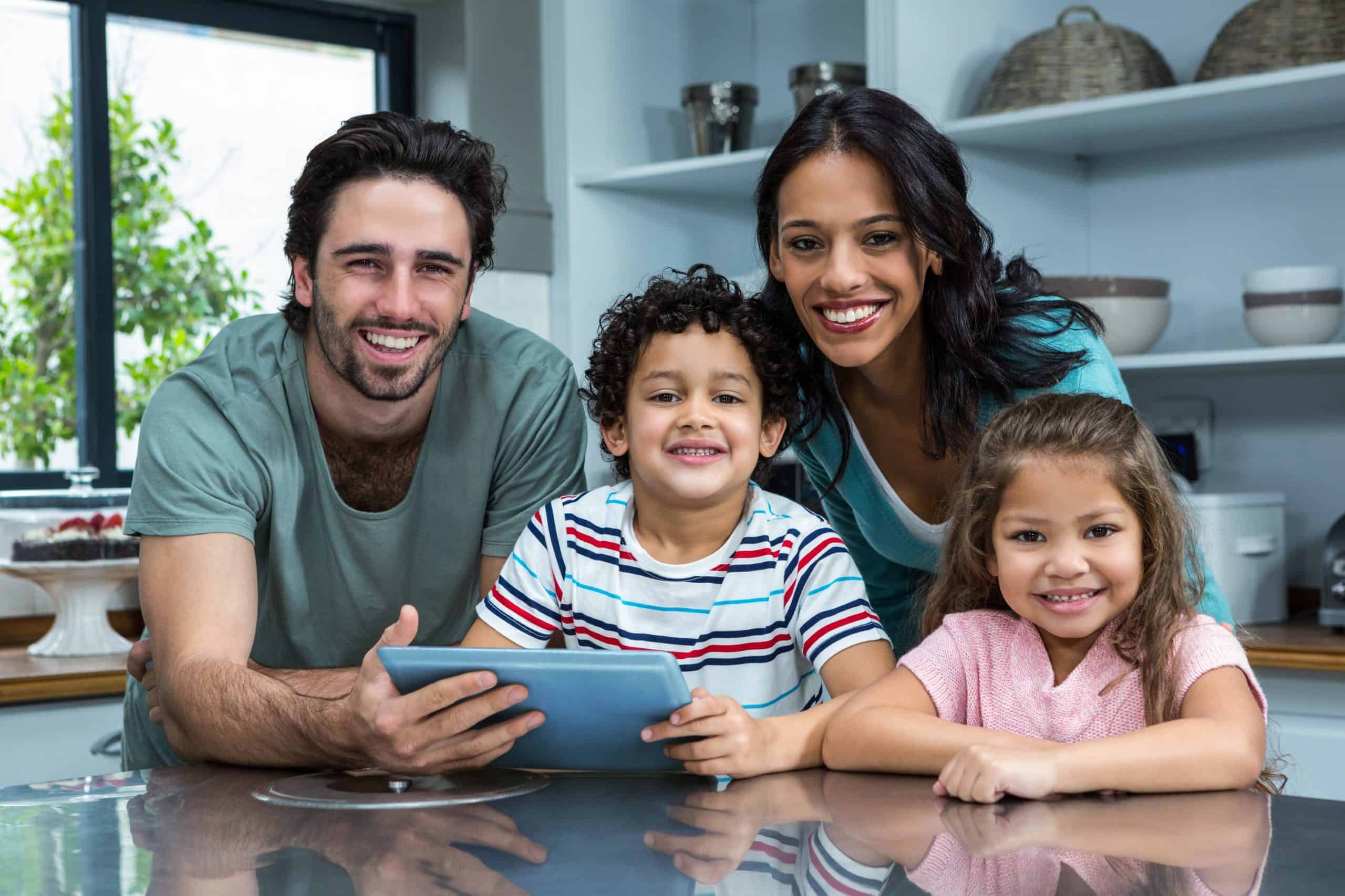 smiling family using tablet kitchen scaled Smile Dentist Toronto