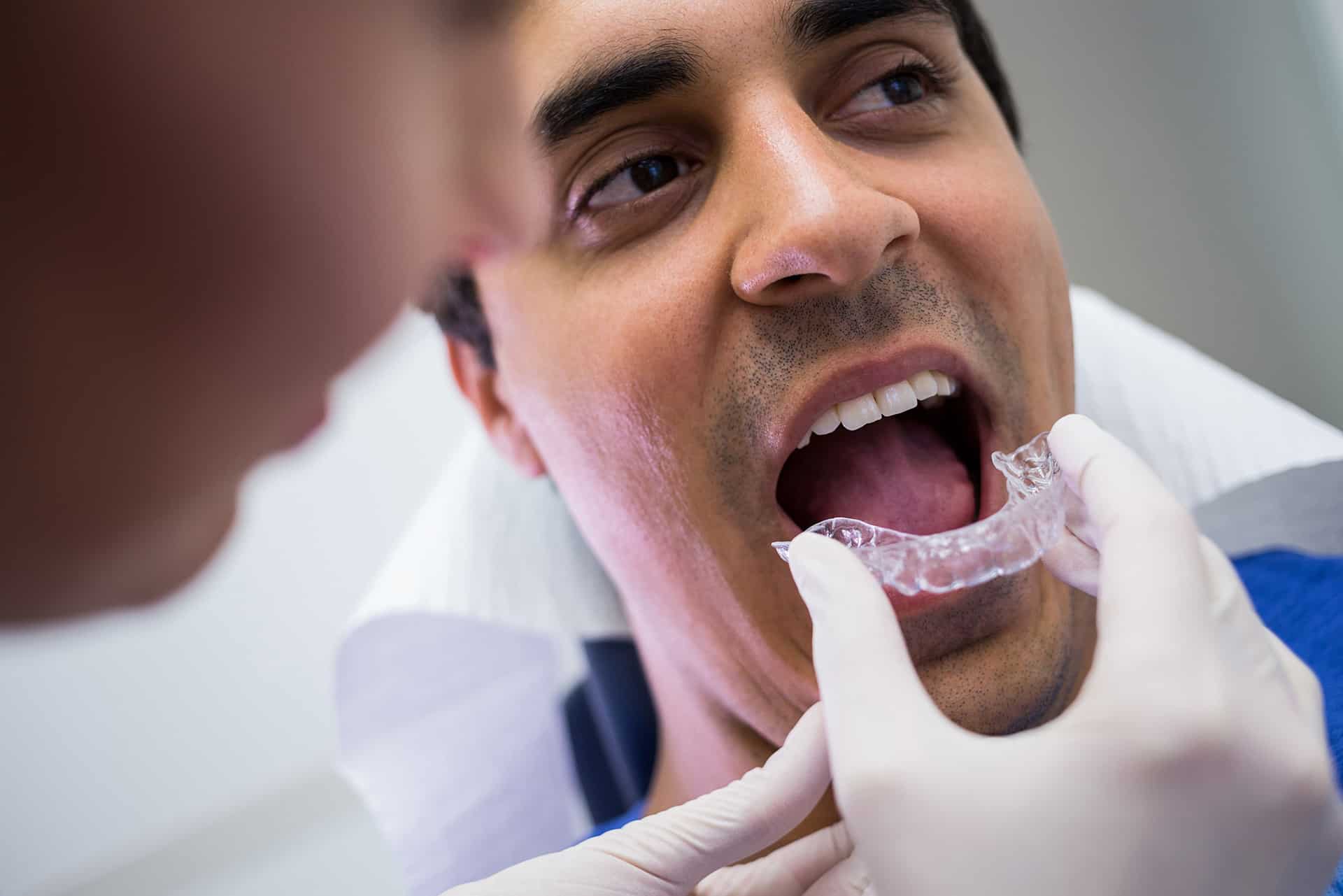 dentist assisting patient wear invisible braces in etobicoke